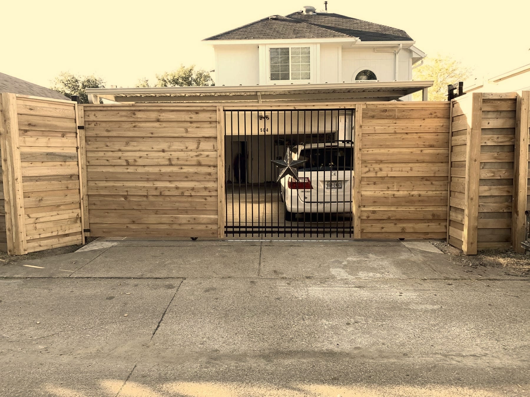 Cedar fencing enclosing a residential back yard with a wrought iron gate, built by A+ Fence Company