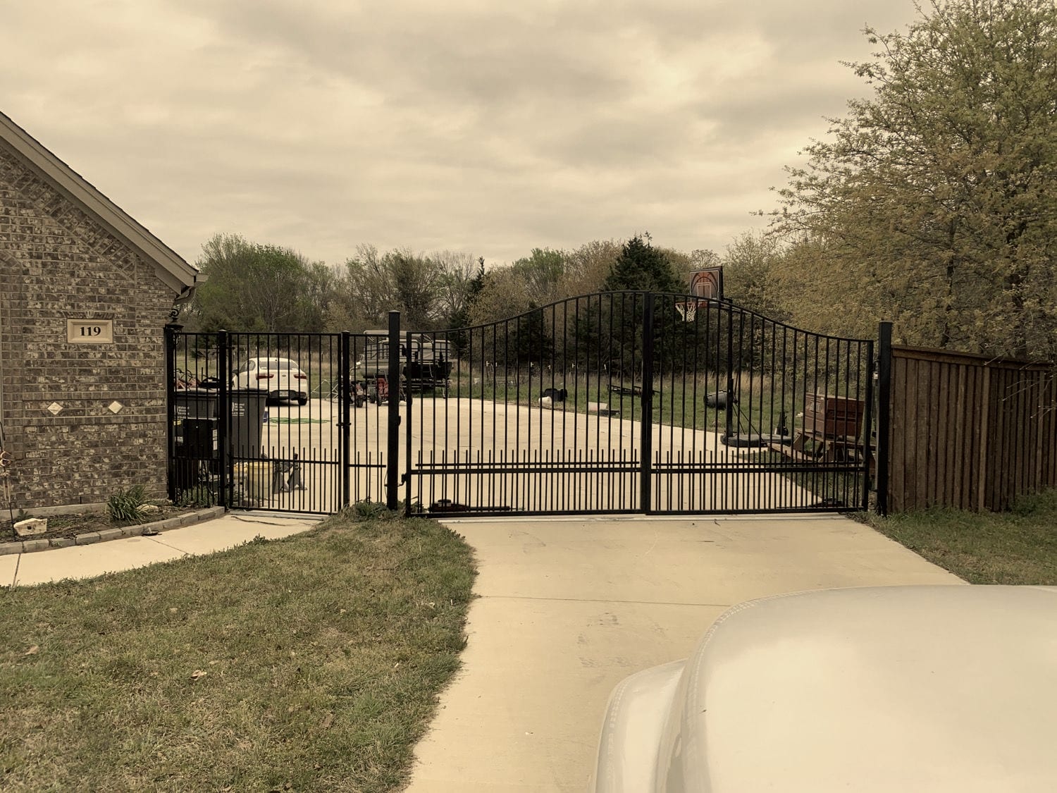 Black wrought iron arched swing gate installed at a brick home by A+ Fence Company