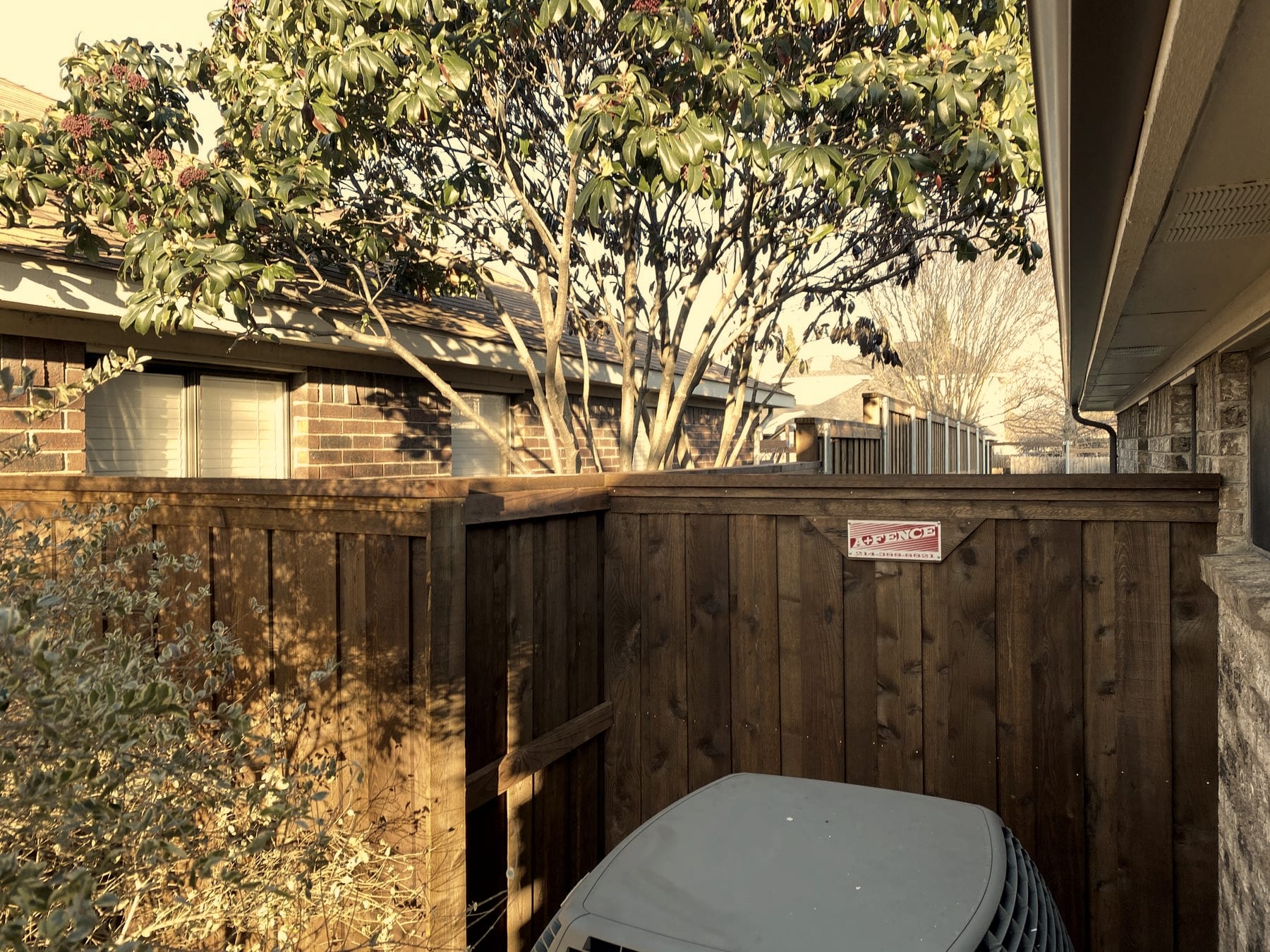 Finished cedar fence run with the A+ Fence Company sticker on the gate